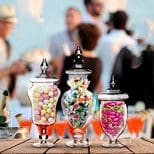 Three glass jars filled with candy on top of a table.