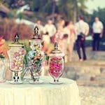 A table with three jars filled with candy.