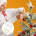 A man in white shirt and tie decorating a christmas tree.