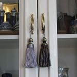 A pair of tassels hanging on the handle of a cabinet.
