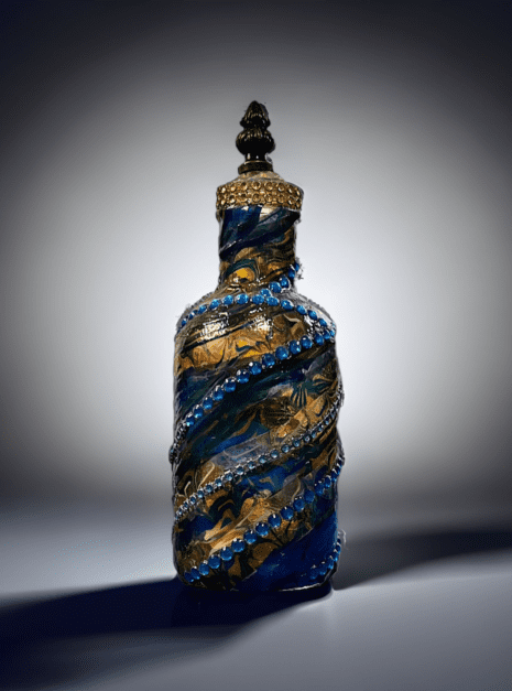 A blue and gold glass bottle with a black top.