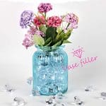 A blue mason jar filled with flowers on top of a table.