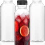 Three glass bottles with a fruit drink in them.