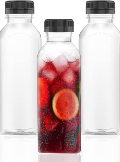 Three glass bottles with a fruit drink in them.