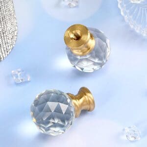 Two Crystal Finials with brass fittings, displayed on a light blue surface, accompanied by decorative items.