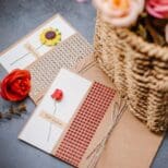 A basket of flowers and two cards on the table.