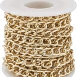 A spool of gold chain on top of white plastic.