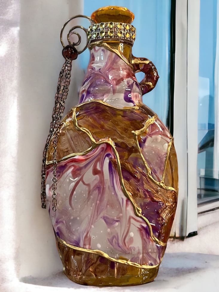 Decorative glass jug with swirling purple and white patterns, featuring a metal chain and ornate golden cap, placed against a window.